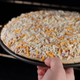 hand putting frozen pizza in oven